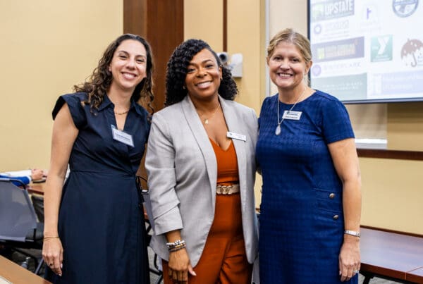 From left to right: Lana Kleiman of Charleston Legal Access, board member Lakesha Jeffries, and Anne Cagwood of Lowcountry Legal Volunteers, smiling and posing for the camera.