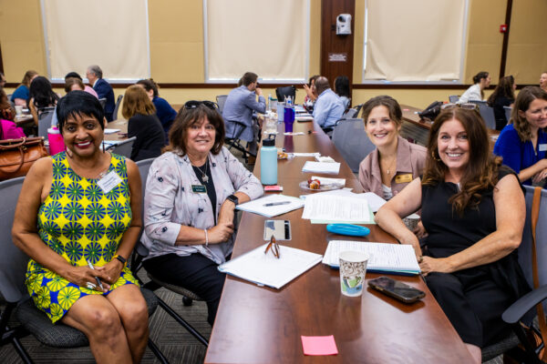 A group of grantees smile together while seated at a table during the networking event.